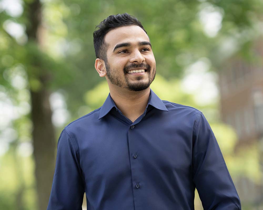 A UMGC graduate in professional clothing smiling in an outdoor location.