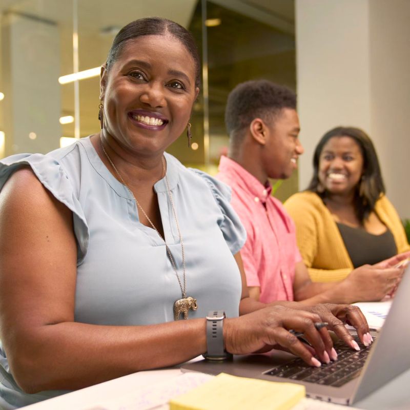 A person typing on a laptop and smiling.