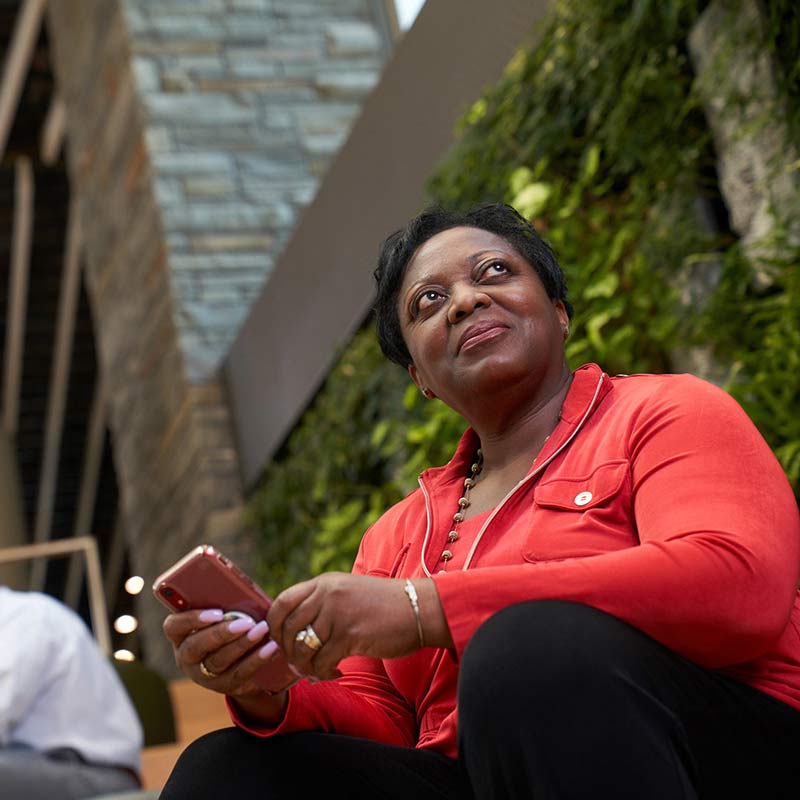 A UMGC student holds her phone in her hands while looking at something in the distance.