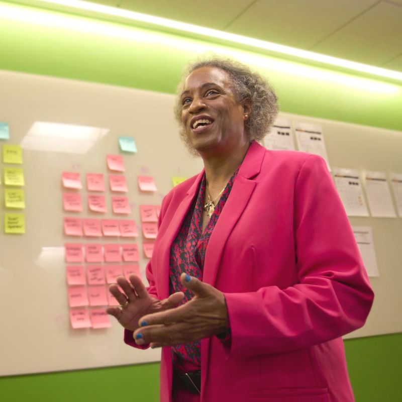 A person standing in front of a whiteboard with sticky notes on it.