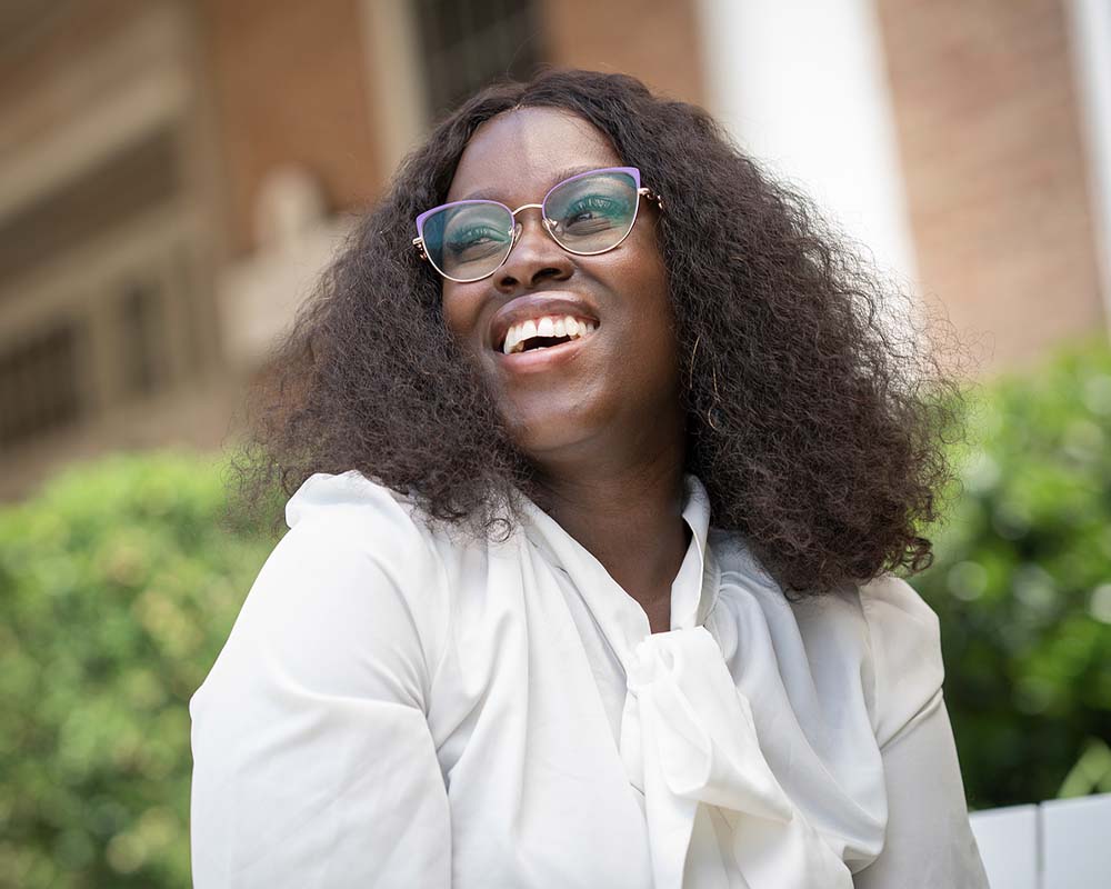 A UMGC graduate in professional clothing smiling in an outdoor location.