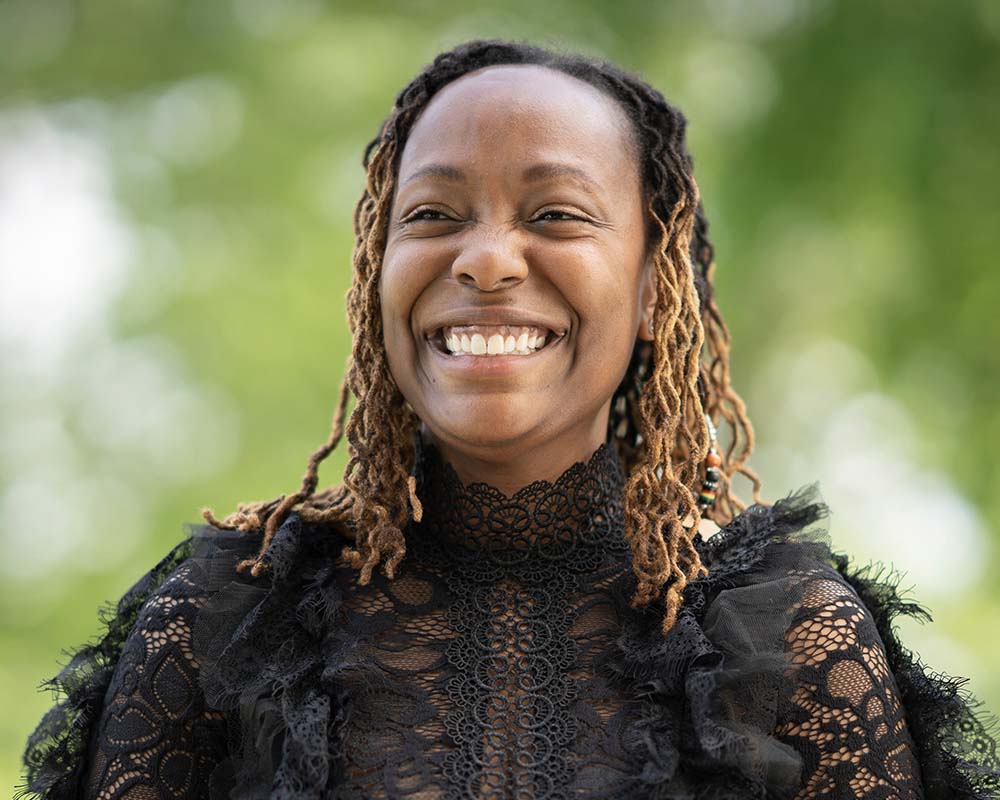 A UMGC graduate in professional clothing smiling in an outdoor location.