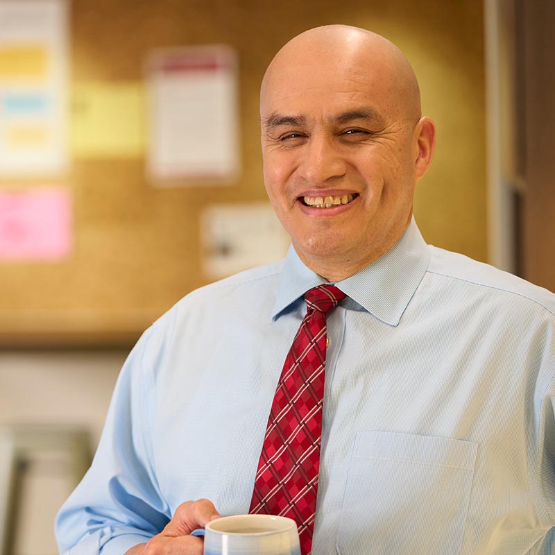 A person holding a coffee mug smiling at the camera.