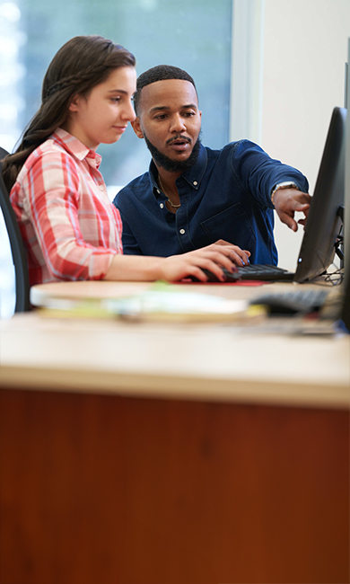 Young male teacher (model - Jamaal Clarke) with middle school aged student in a computer lab - Shady Grove - photo credit Cade Martin Photography