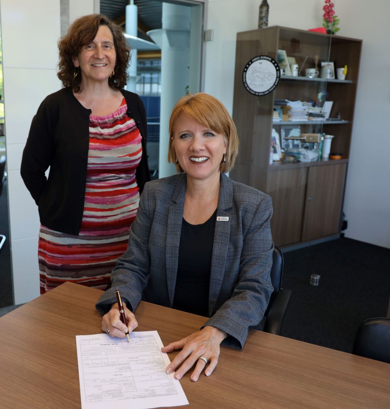 Patricia Coopersmith, vice president and director of UMGC’s Europe Division, signs the DoD contract, as Monika Denburg, director of Institutional Research and Contract Compliance in the Europe Division, looks on.