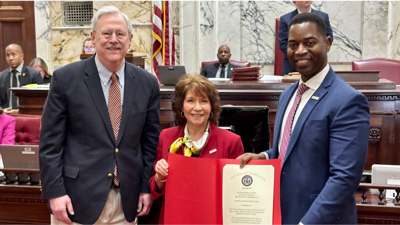 UMGC President Gregory Fowler (right) and alumna Patricia Toregas are presented with the Maryland Senate resolution by Sen. Jim Rosapepe (D).