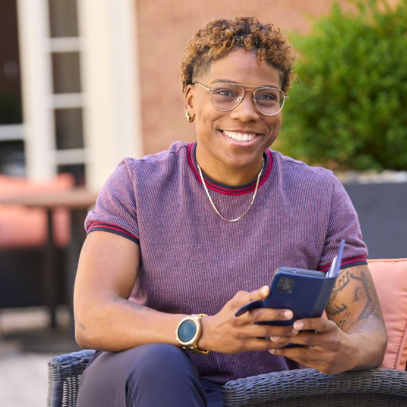 A person holding a cell phone and smiling.