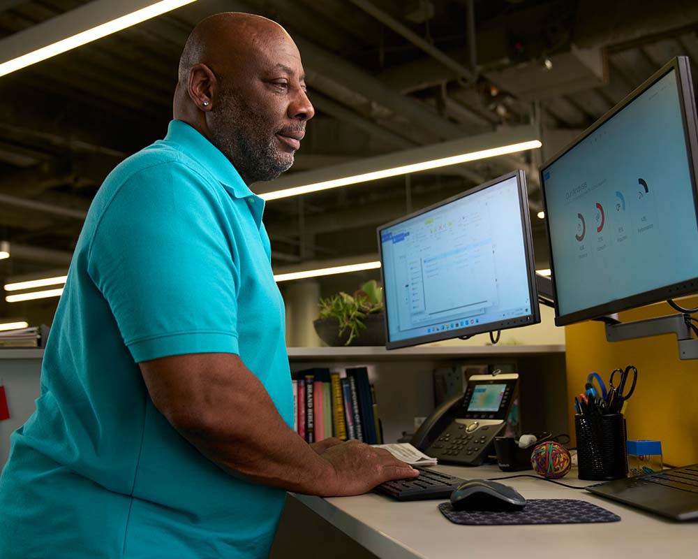 A person typing on a keyboard surrounded by computer screens.