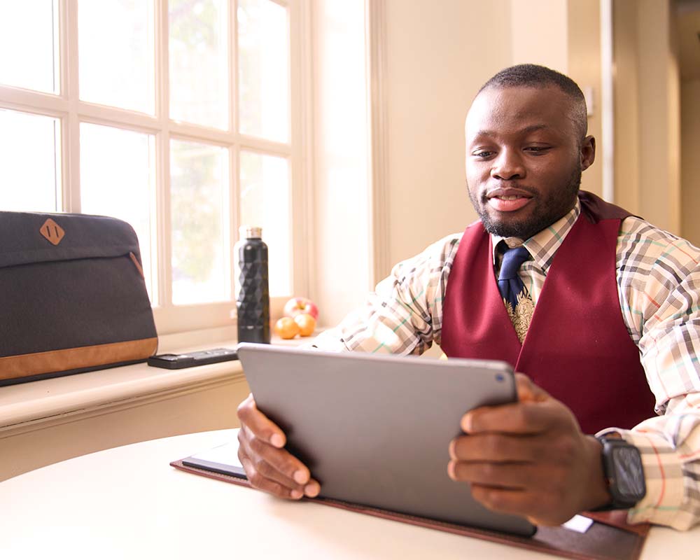 A person using a tablet by a window.