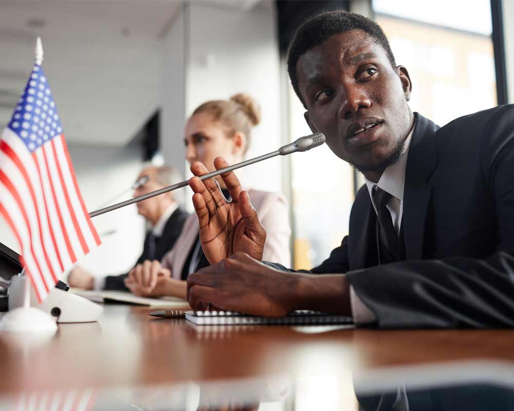 A person holding a microphone at a desk.