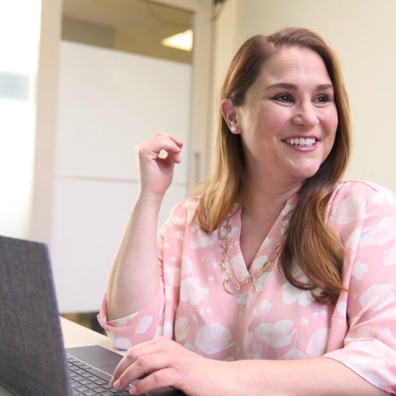 A person typing on a laptop and smiling.