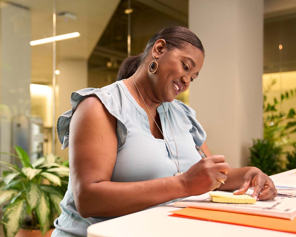 A person smiling and taking notes.