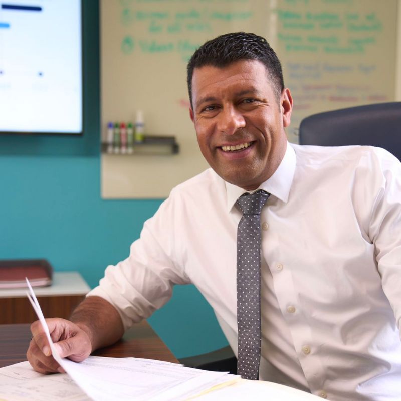 A person in a tie sitting and smiling.