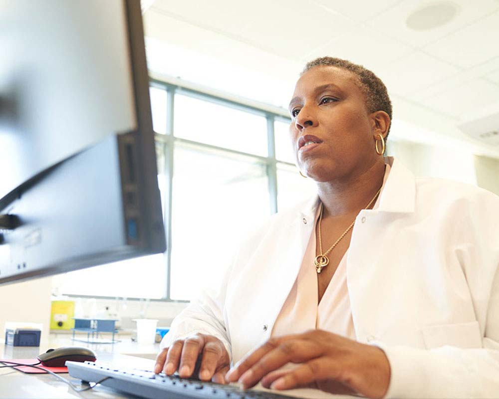 A UMGC faculty member is typing something on a computer.