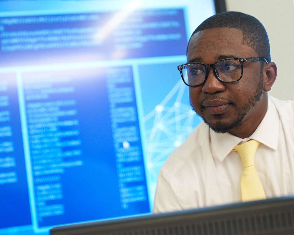 A UMGC student, who is pursuing bachelor’s and master’s degrees in cybersecurity and computer networking, is looking at something on a computer. 
