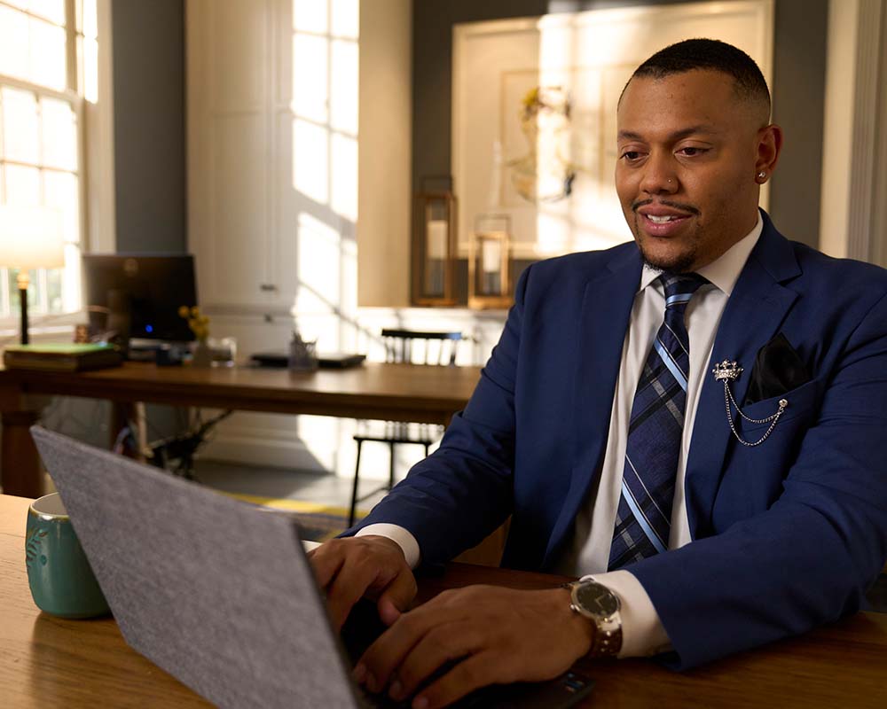 A person in a suit typing on a laptop.