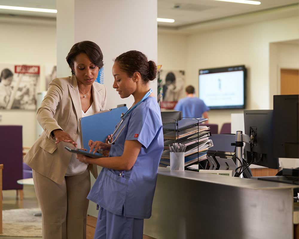 A UMGC student, who is pursuing a master’s degree in healthcare administration and an MBA, is talking to someone in medical scrubs. 