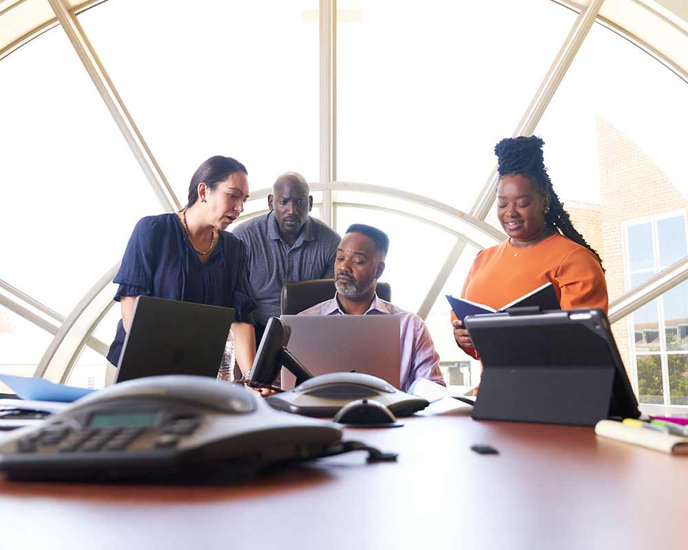 A UMGC student, who is pursuing a bachelor’s degree in human resources management, and another UMGC student, who is pursuing a master’s degree in human resources management, are talking with a group of other people. 