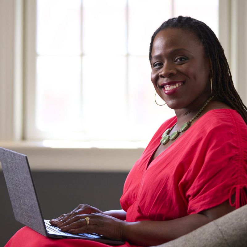 A person typing on a laptop and smiling.