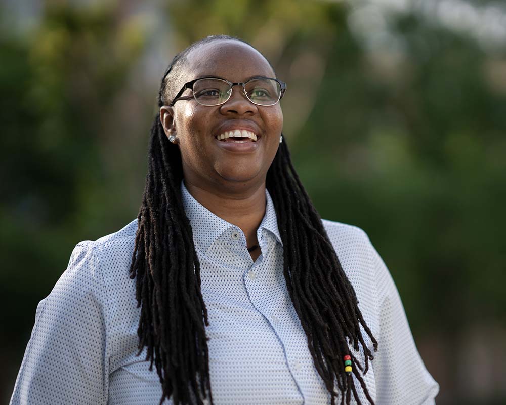 A UMGC graduate in professional clothing smiling in an outdoor location.