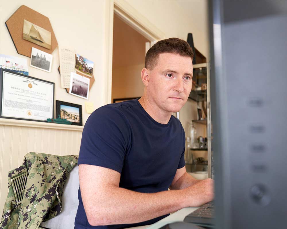 A person in their home office looking at a desktop computer.