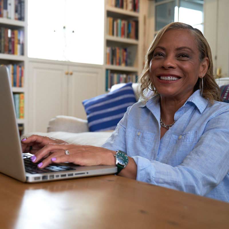 A person typing on a laptop and smiling.